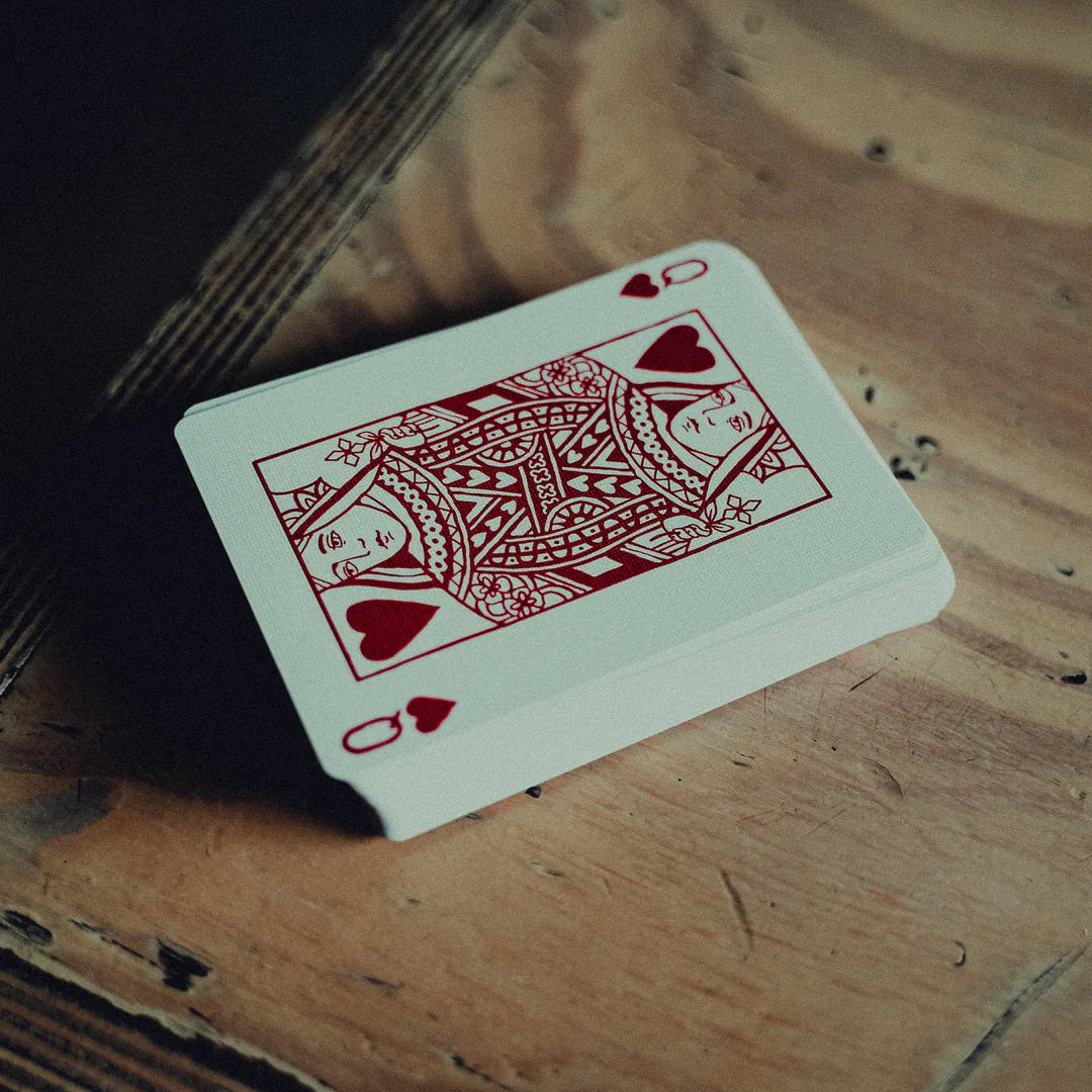 Red playing card with a heart symbol on a wooden surface