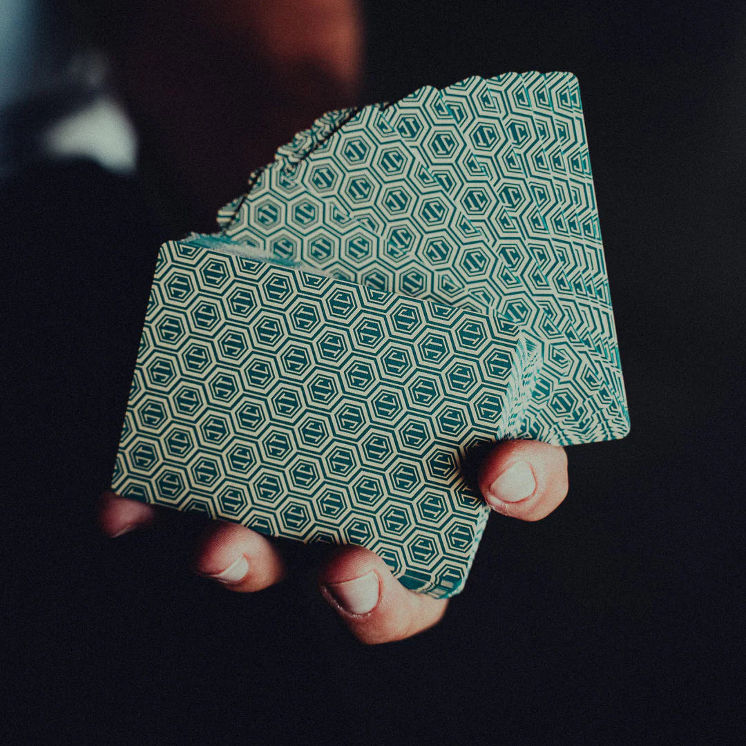 Hand holding a stack of green NO BORDERS: Series 1 patterned cards against a dark background