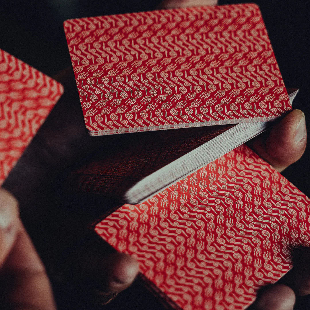 Red crown NO BORDERS: Series 2 Playing Cards with a white pattern held by a person against a dark background