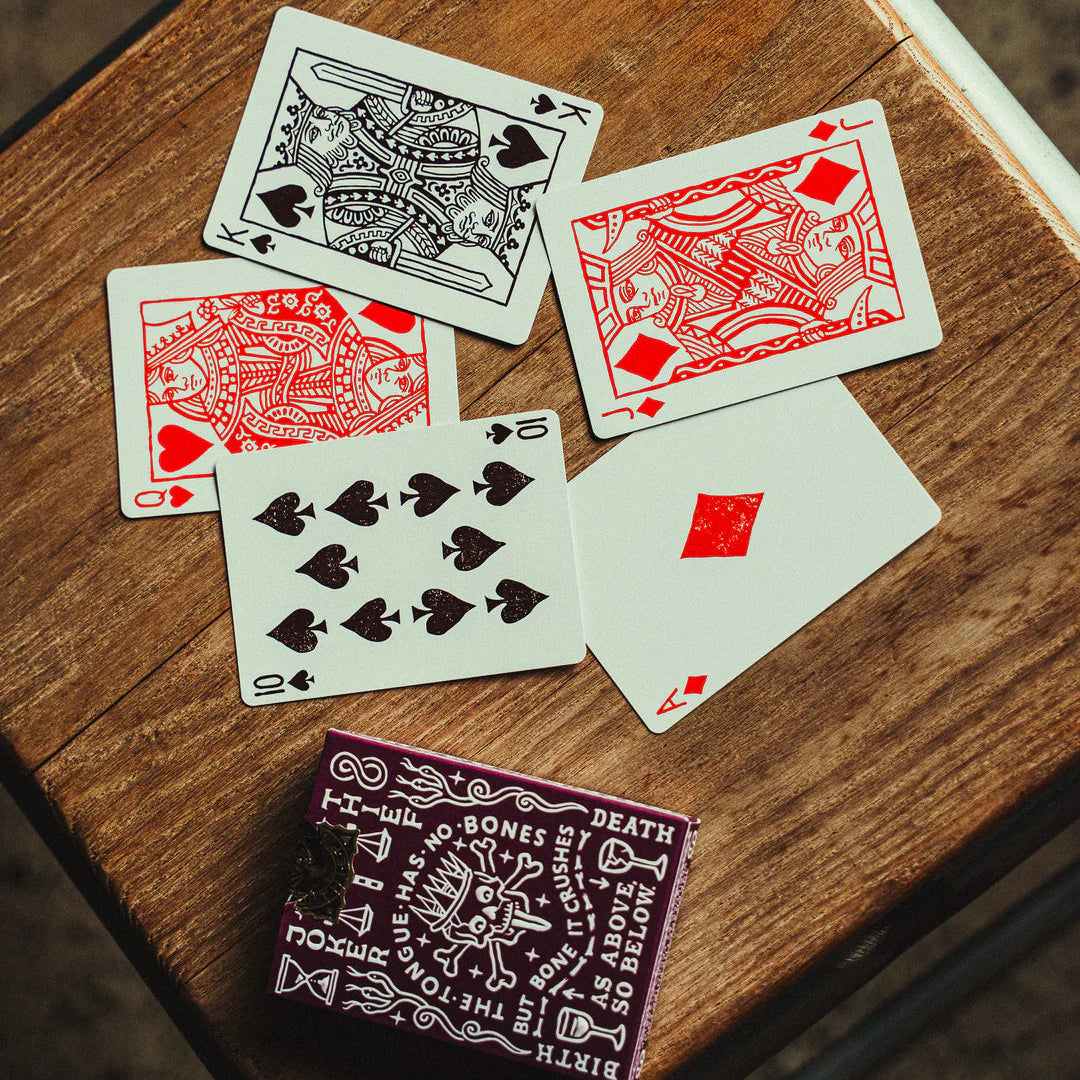 Crown: Royal Purple Edition Playing cards on a wooden surface with a bandana featuring text.