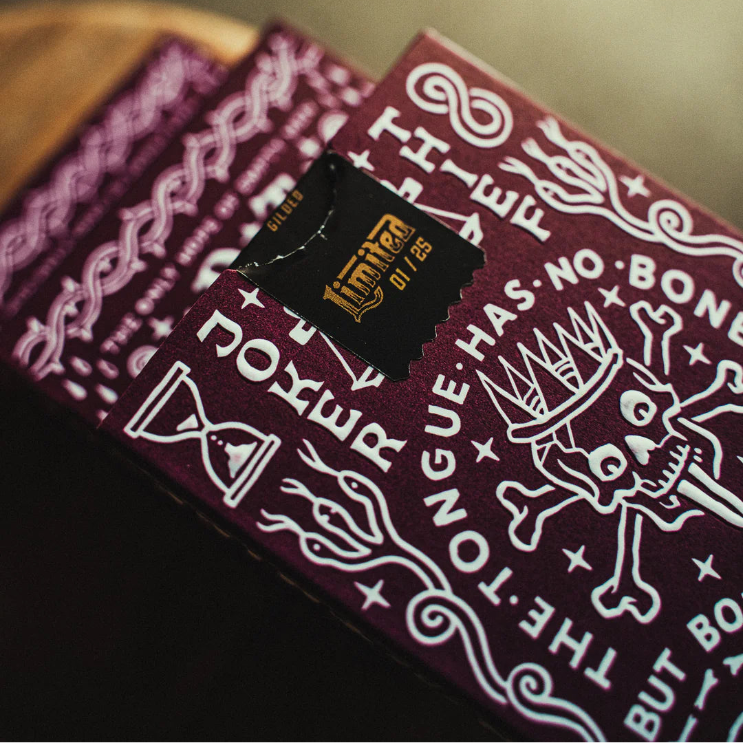 Close-up of a deck of Crown: Royal Purple Edition cards with intricate designs and text on a dark surface.