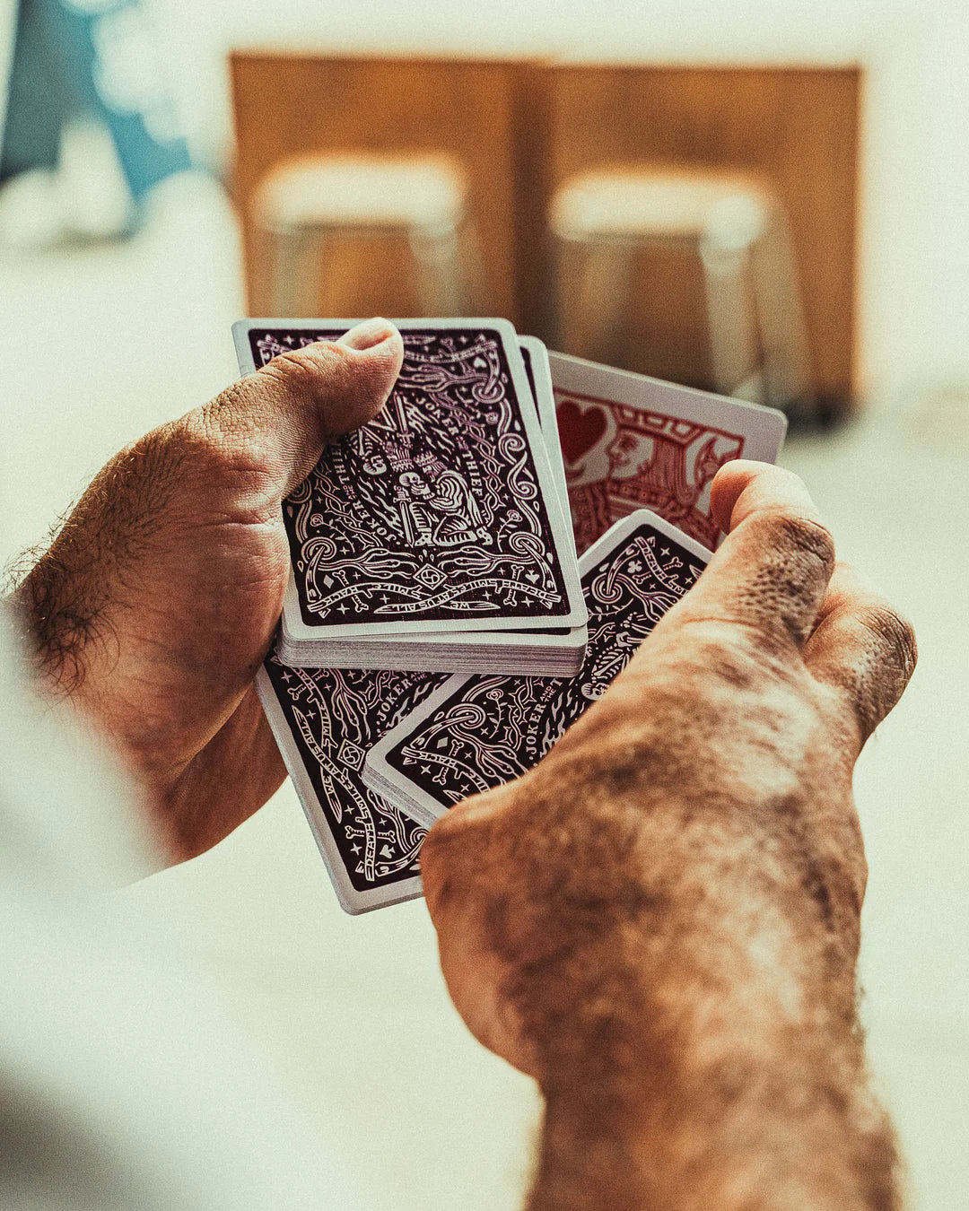 Close-up of hands holding Crown: Royal Purple Edition playing cards with a blurred background