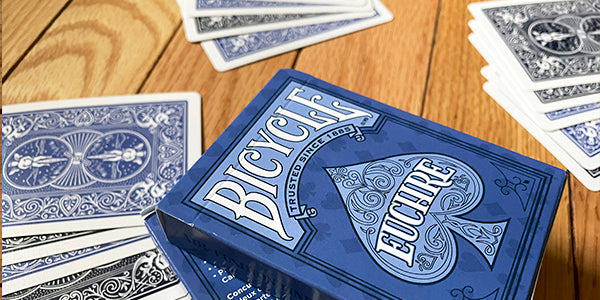 Blue and white Euchre playing cards with 'Bicycle' branding on a wooden surface