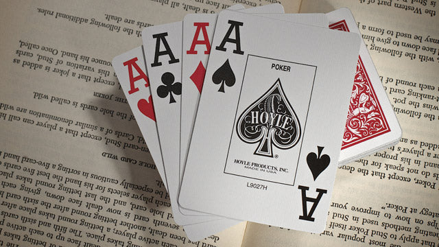 Four playing cards with Ace symbols on a book page