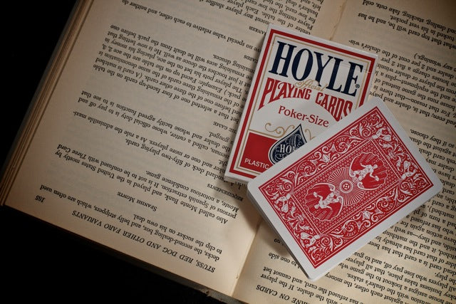 Two red playing cards with 'Hoyle' branding on an open book.