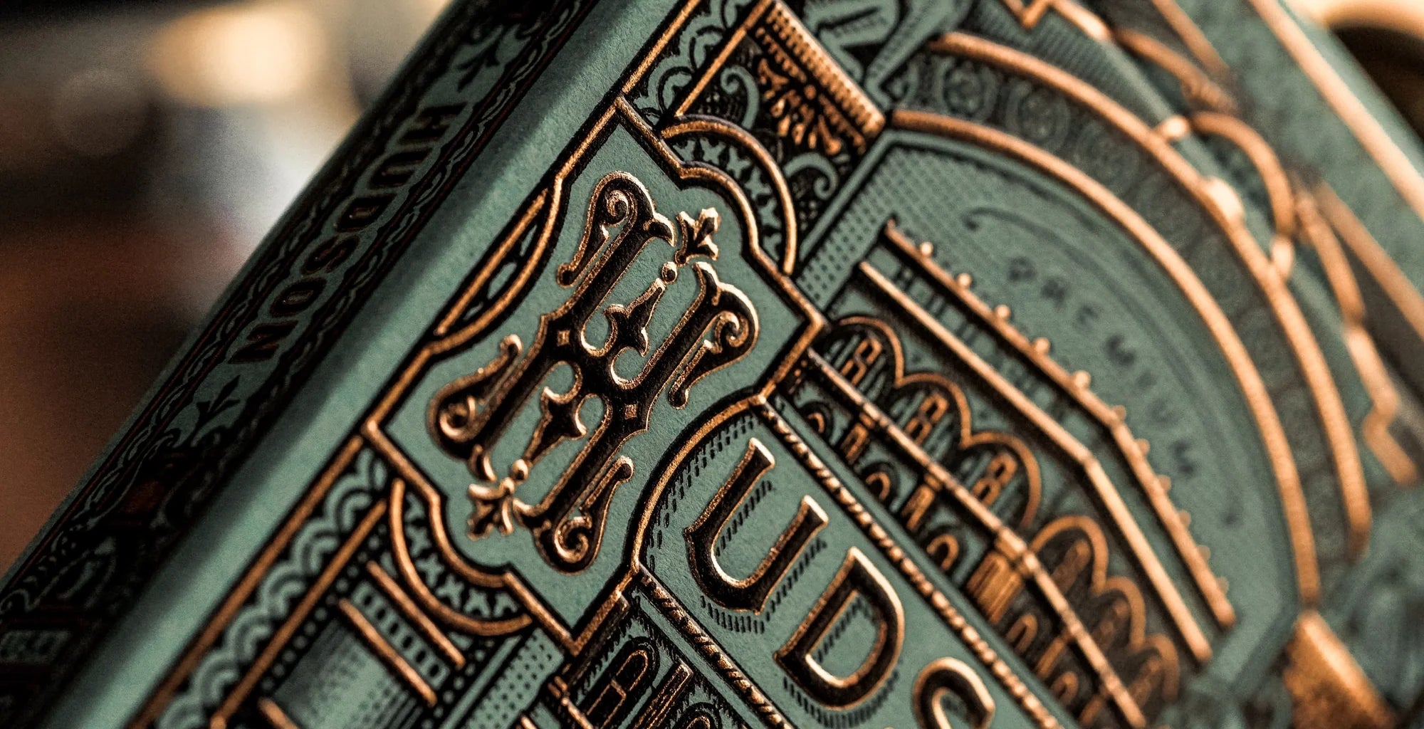 Close-up of Theory11 Hudson monogram and copper foil embossing on the tuck box