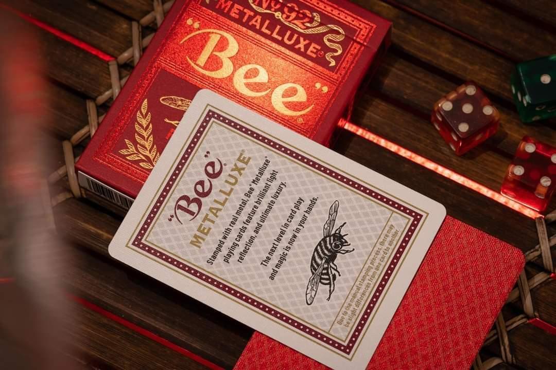 Bee Metalluxe playing cards with red box and card on a wooden surface.