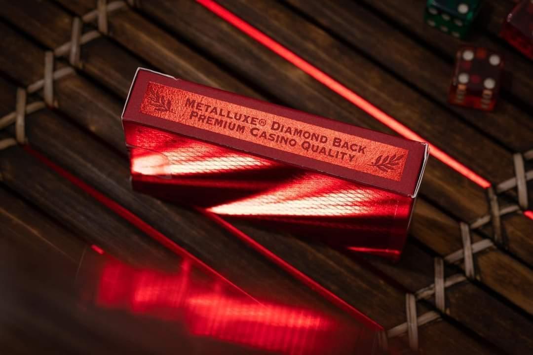 Red Bee playing cards with 'Metalluxe' branding on a wooden surface.