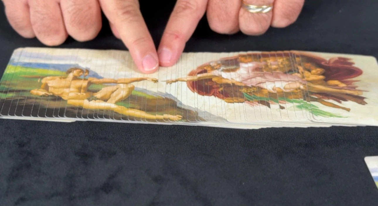 Hand holding a folded piece of paper with classical painting illustrations on a dark surface
