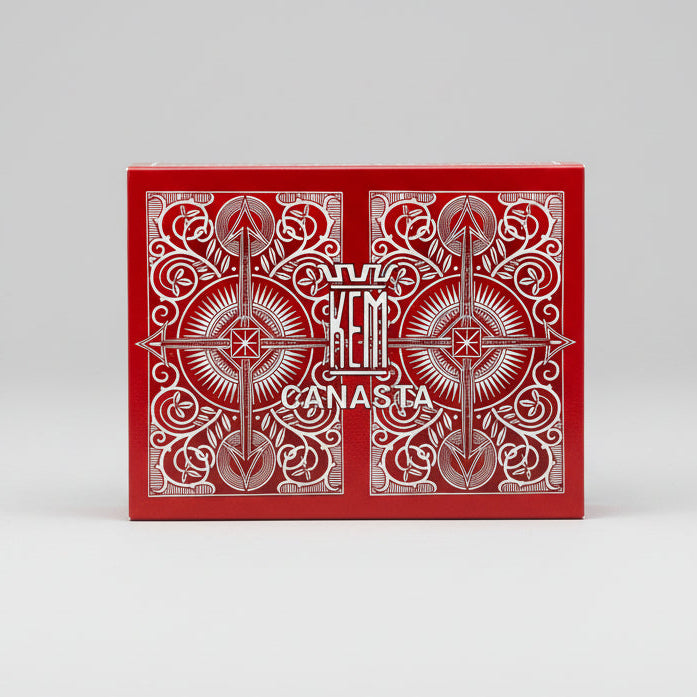 Red and white playing card box with 'KEM Canasta' branding on a light gray background