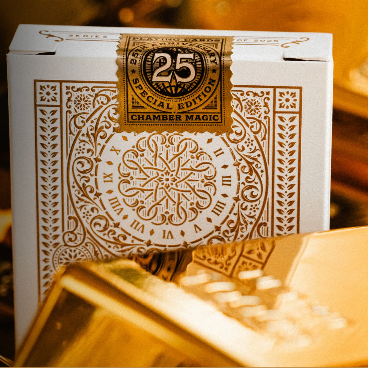 Back of Tycoon 25th Anniversary tuck with ornate gold clockwork pattern and 25th Anniversary Chamber Magic seal.