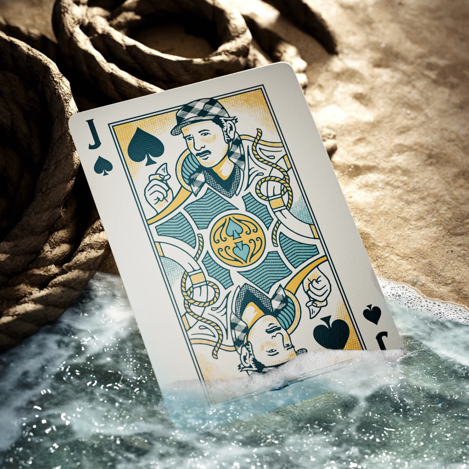 Theory11 JAWS custom jack of spades court card beside ocean surf