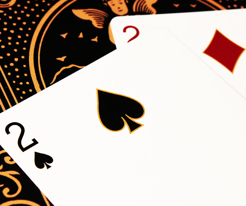 Two playing cards with black spade symbol and red heart symbol on a patterned background