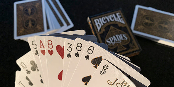 Playing cards with Bicycle Spades branding on a dark background