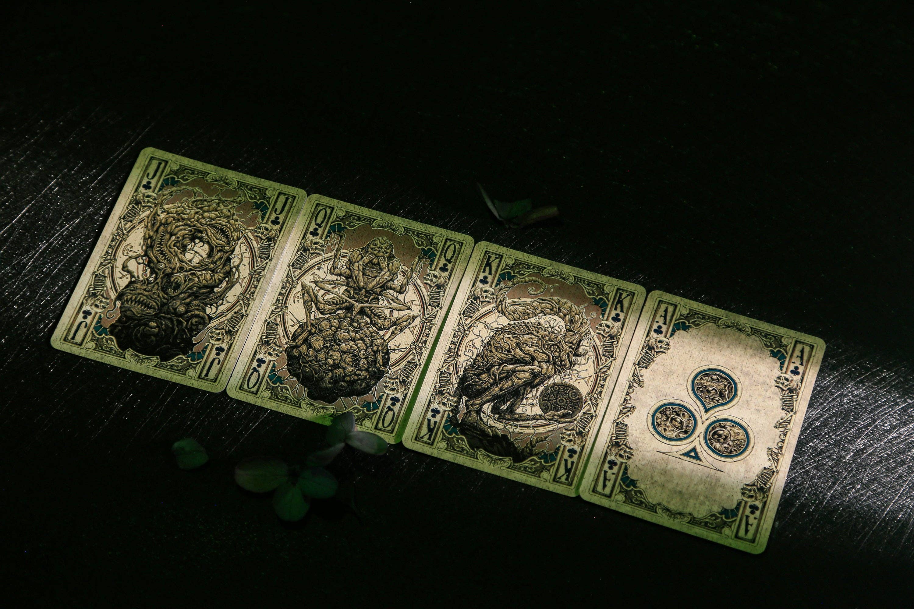 Four playing cards with intricate designs on a dark surface
