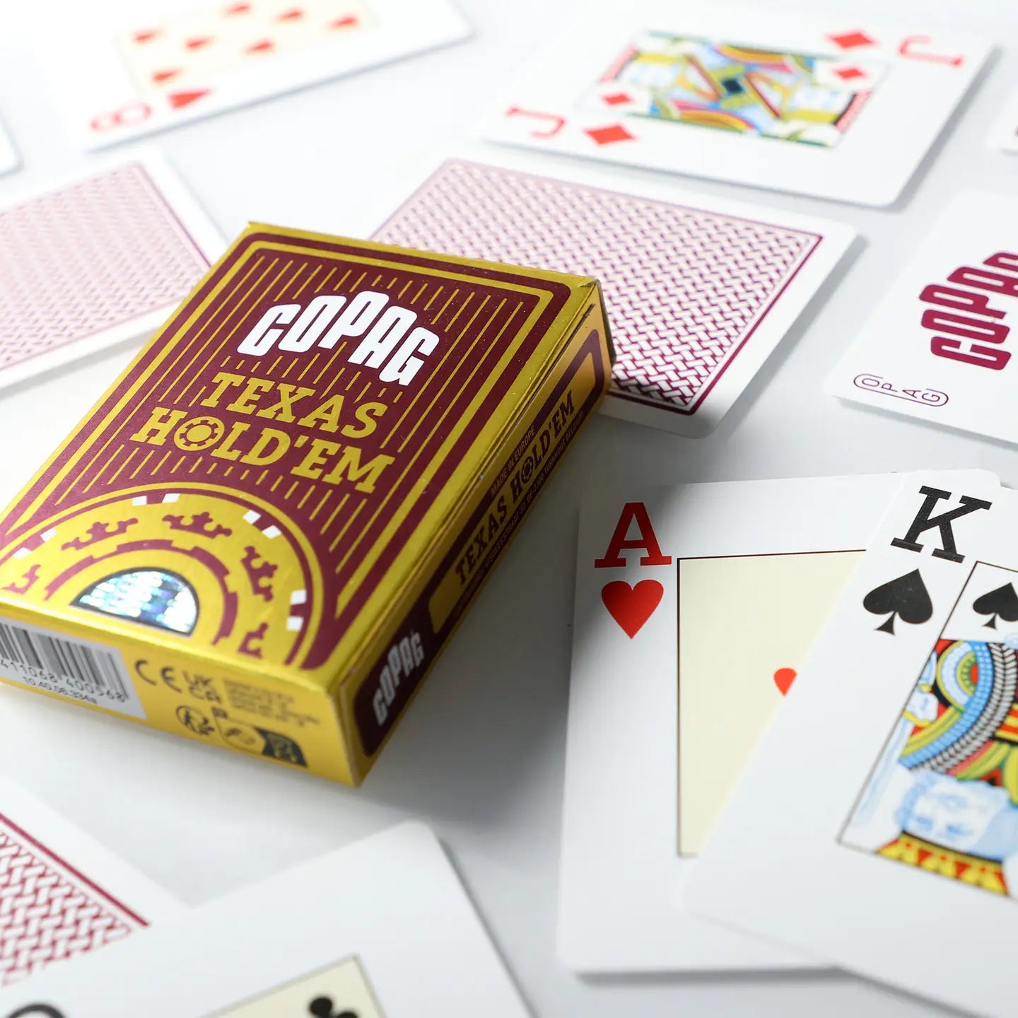 Copag Texas Hold'em playing cards with a box and cards spread out on a white surface.