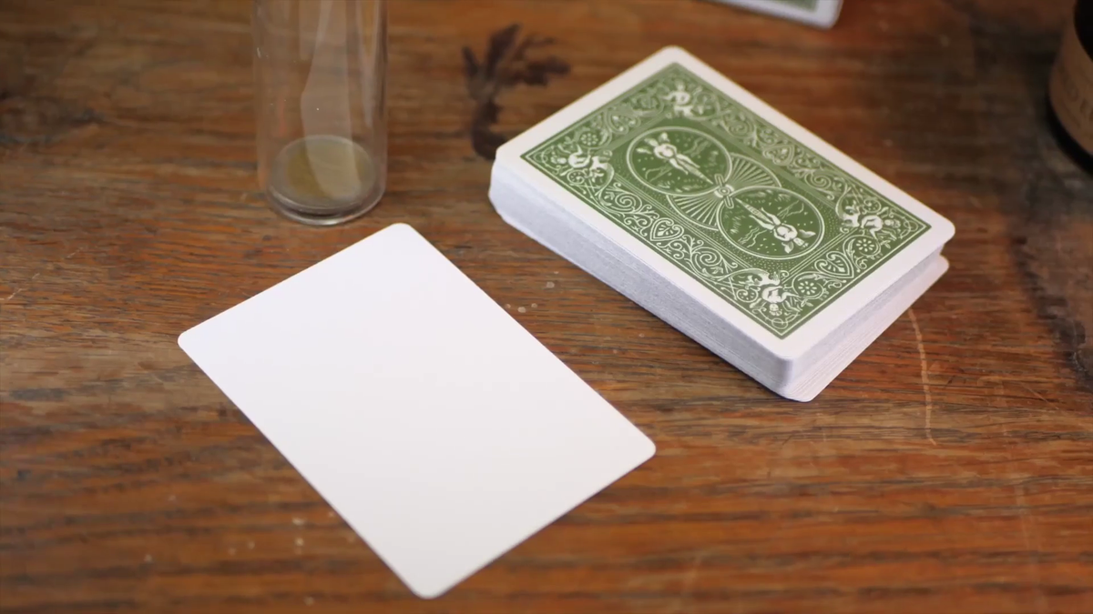 Bicycle Metallic Emerald deck and included blank-face gaff card on a wooden tabletop