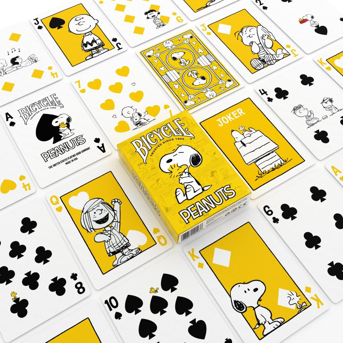 Bicycle Peanuts tuck box surrounded by character courts, the Ace of Spades, a Snoopy Joker, number cards, and a yellow card back.