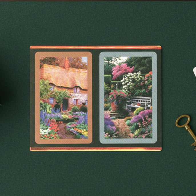 Cardboard Congress card decks with scenic illustrations of a thatched-roof cottage and a rose garden.