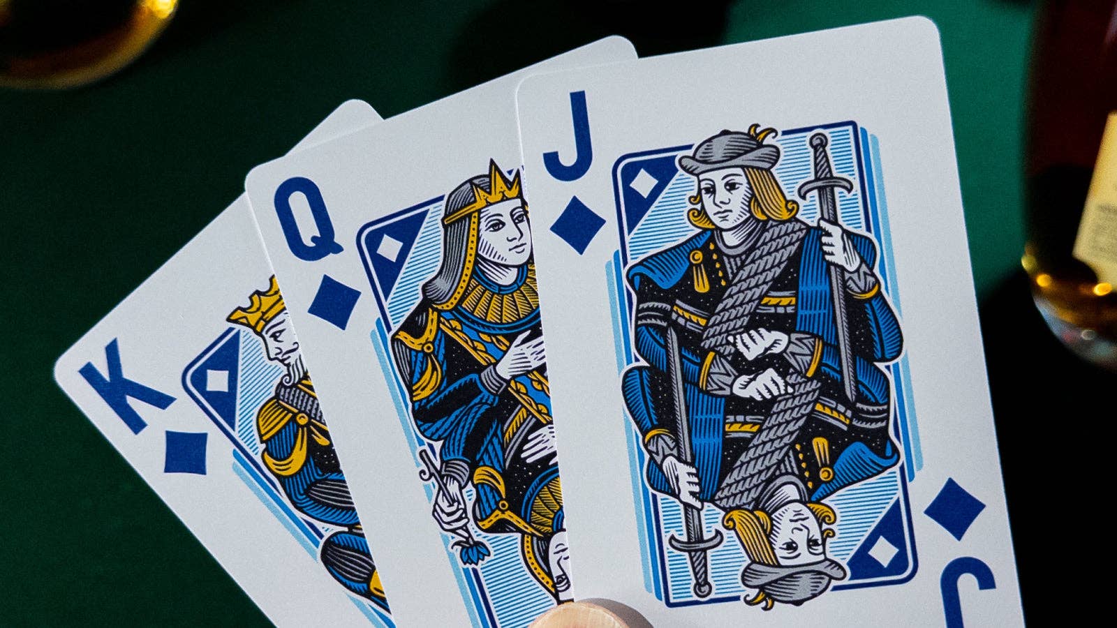 Four Vanda Aces 2.0 playing cards featuring kings, queens, and jacks on a green surface.