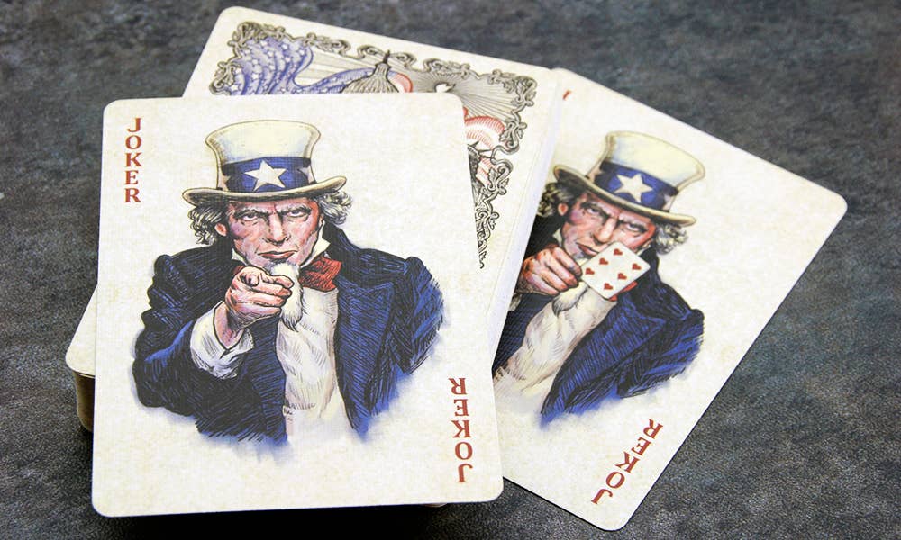 Two playing cards featuring Uncle Sam with joker text on a dark surface