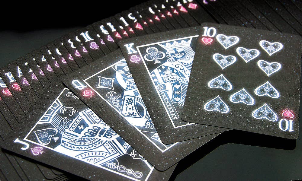 Black playing cards with blue designs on a dark surface