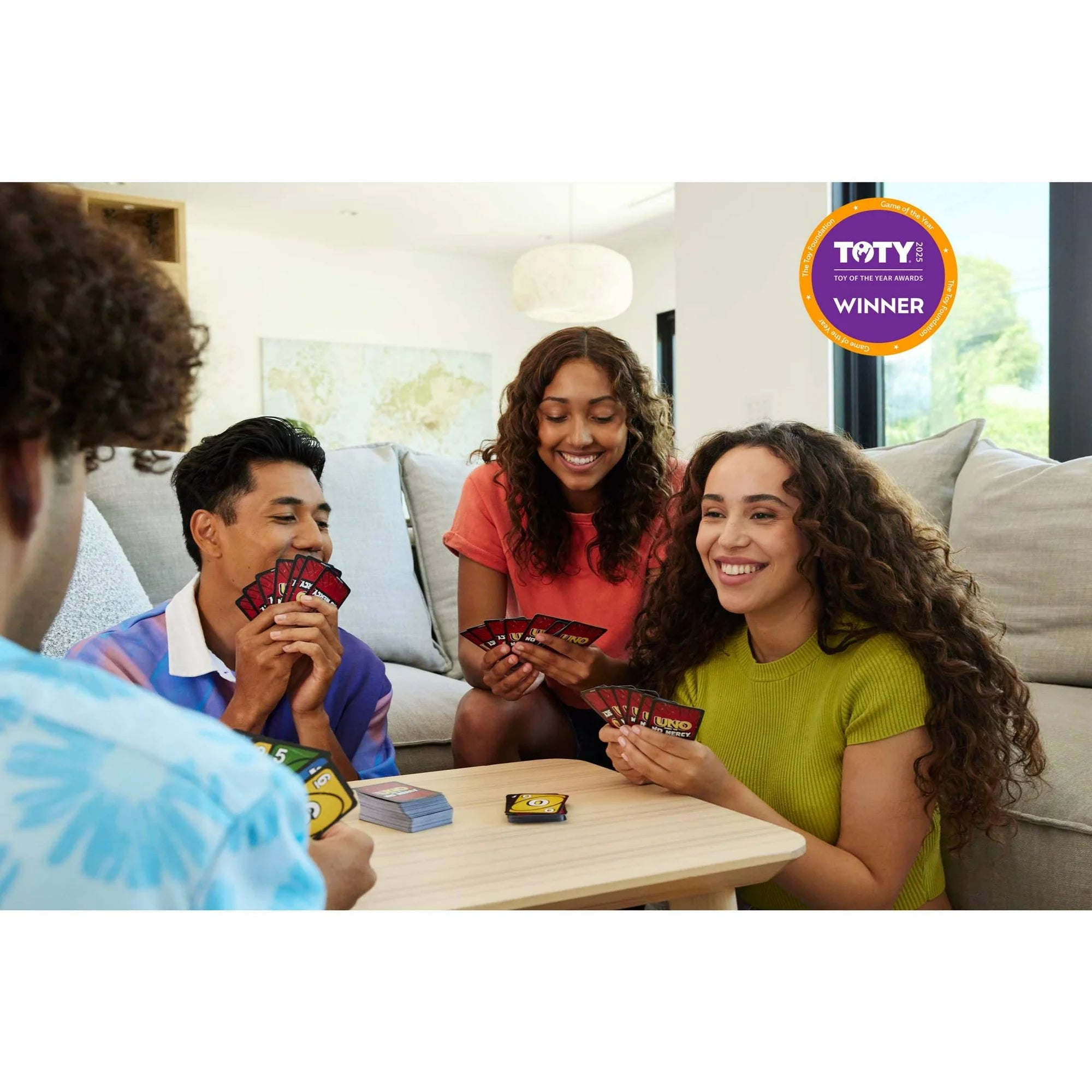 Four friends playing UNO Show Em No Mercy together in a living room with a TOTY Winner badge in the corner.