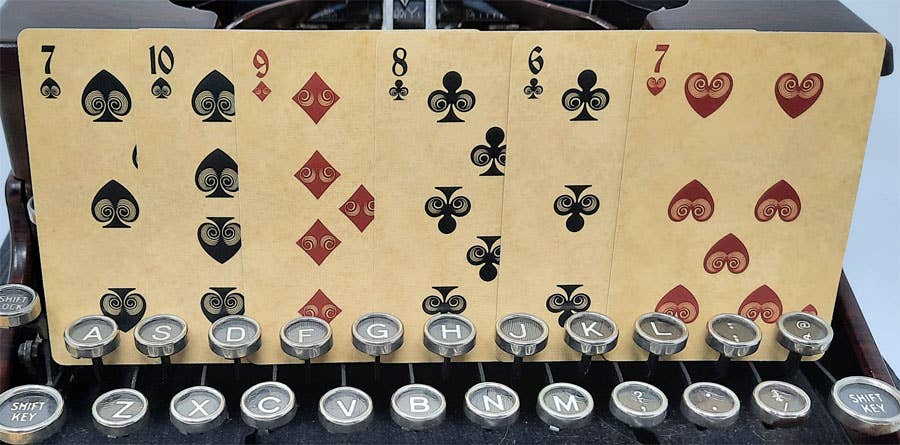Playing cards on top of a typewriter with visible keys