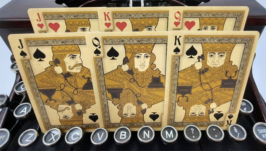 Four playing cards featuring kings of different suits on a typewriter.