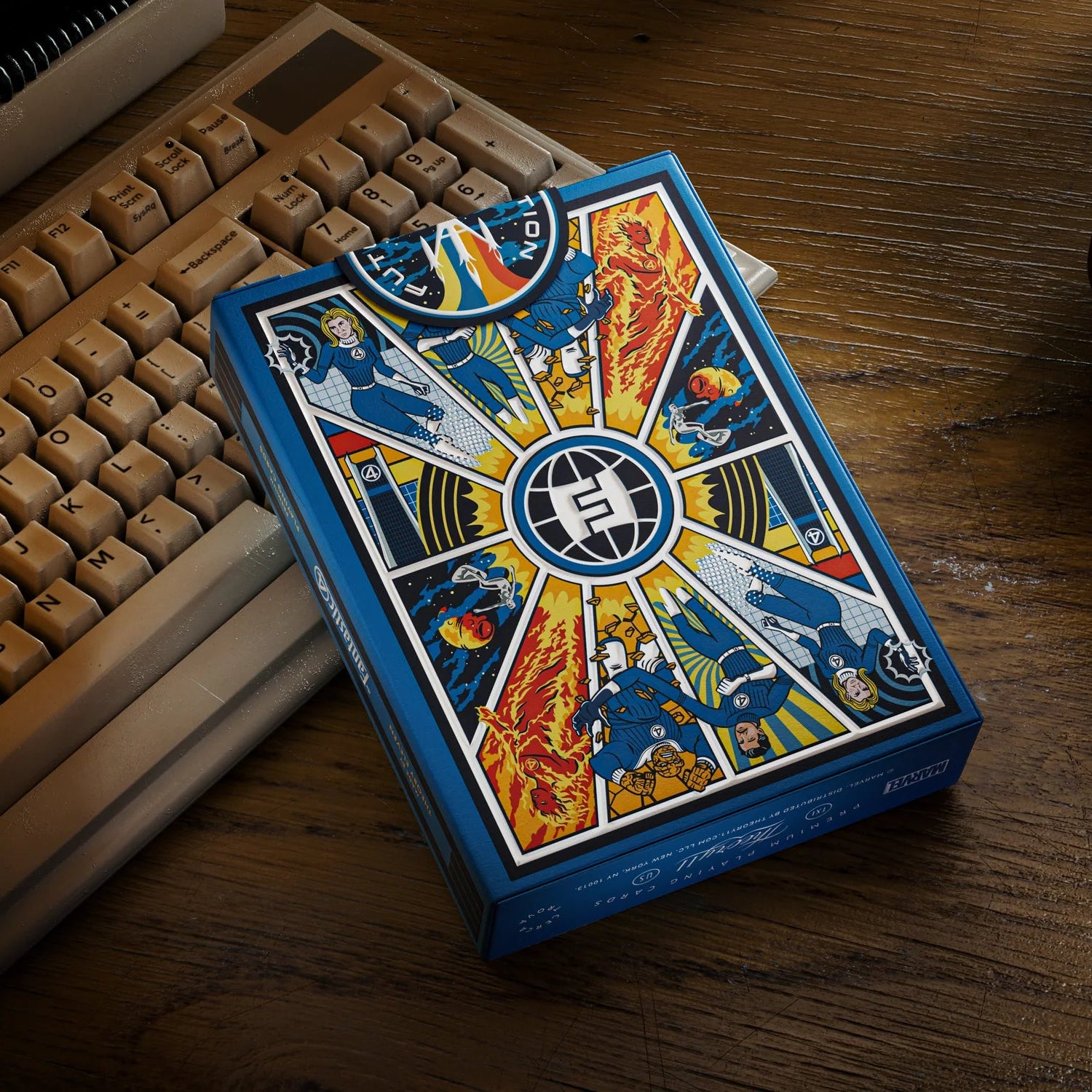 Playing card box with colorful design on a wooden surface next to a keyboard