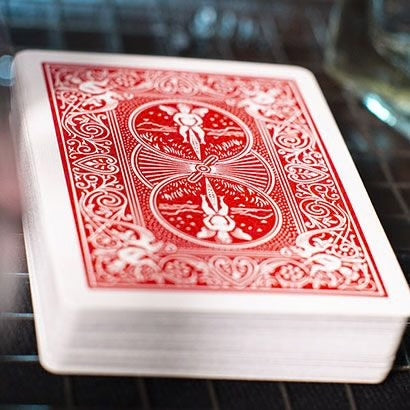 Close-up of a deck of red Bicycle playing cards with rider back designs on a metallic surface.