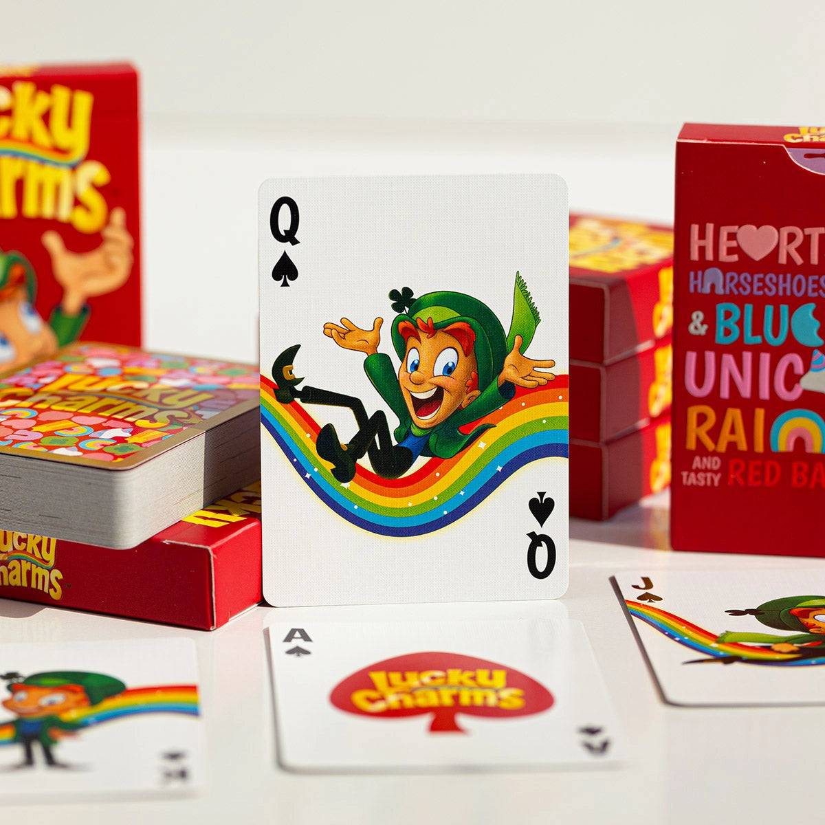 Lucky Charms Queen of Spades showing Lucky on a rainbow, with the branded Ace and other court cards nearby.