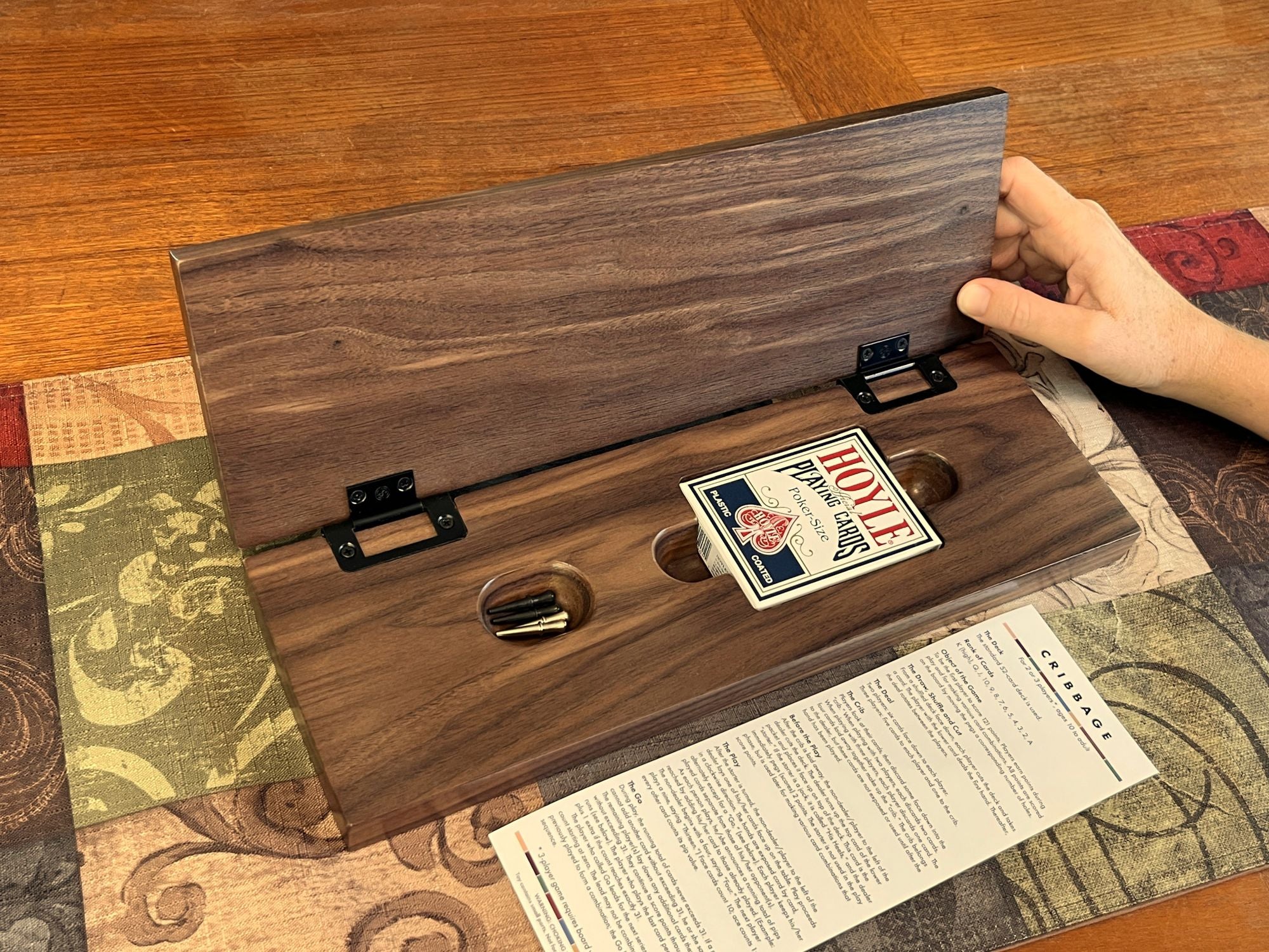 Wooden cribbage box with a card inside on a patterned surface