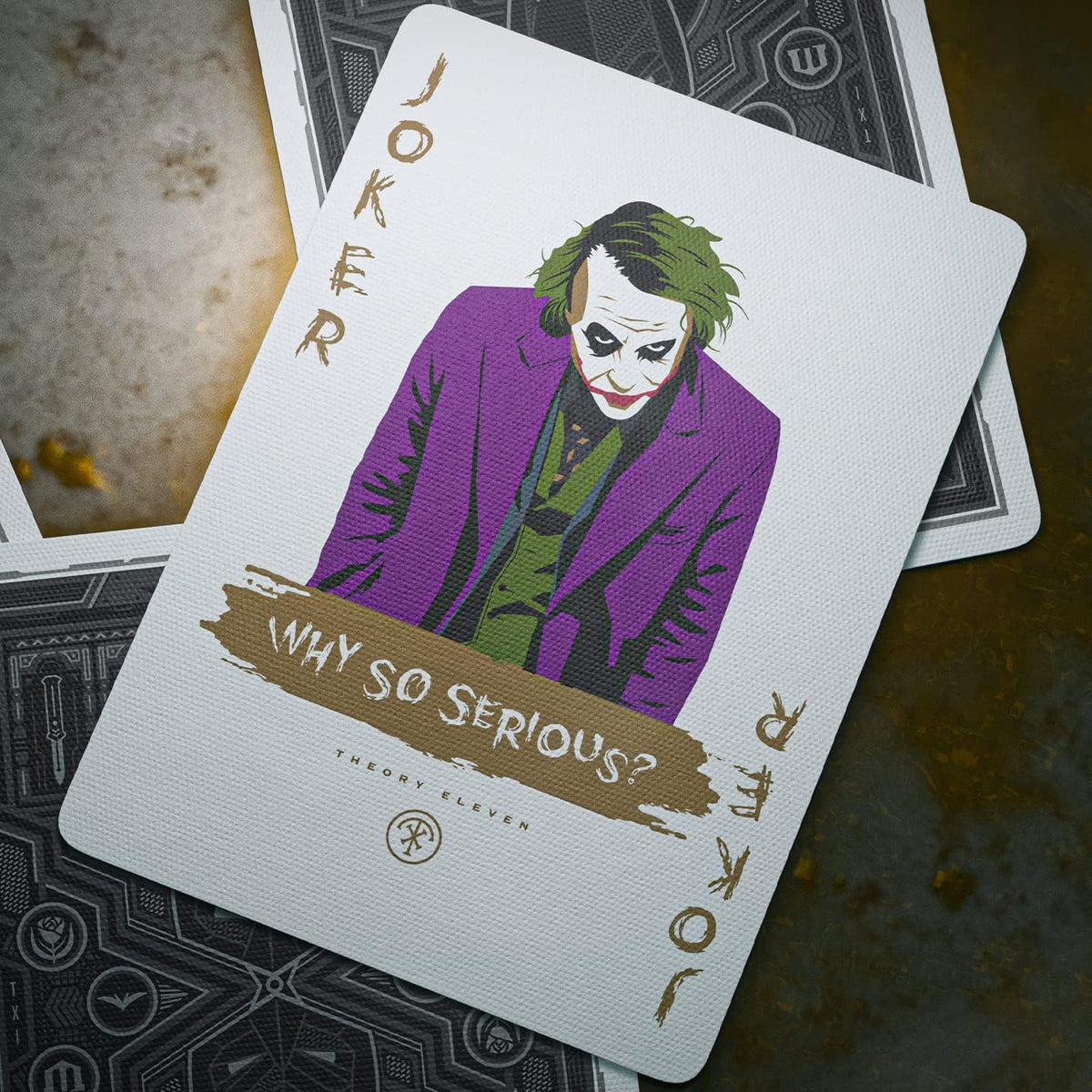 The Joker card from theory11 The Dark Knight Playing Cards, showing a purple jacket, green hair, and Why So Serious lettering.