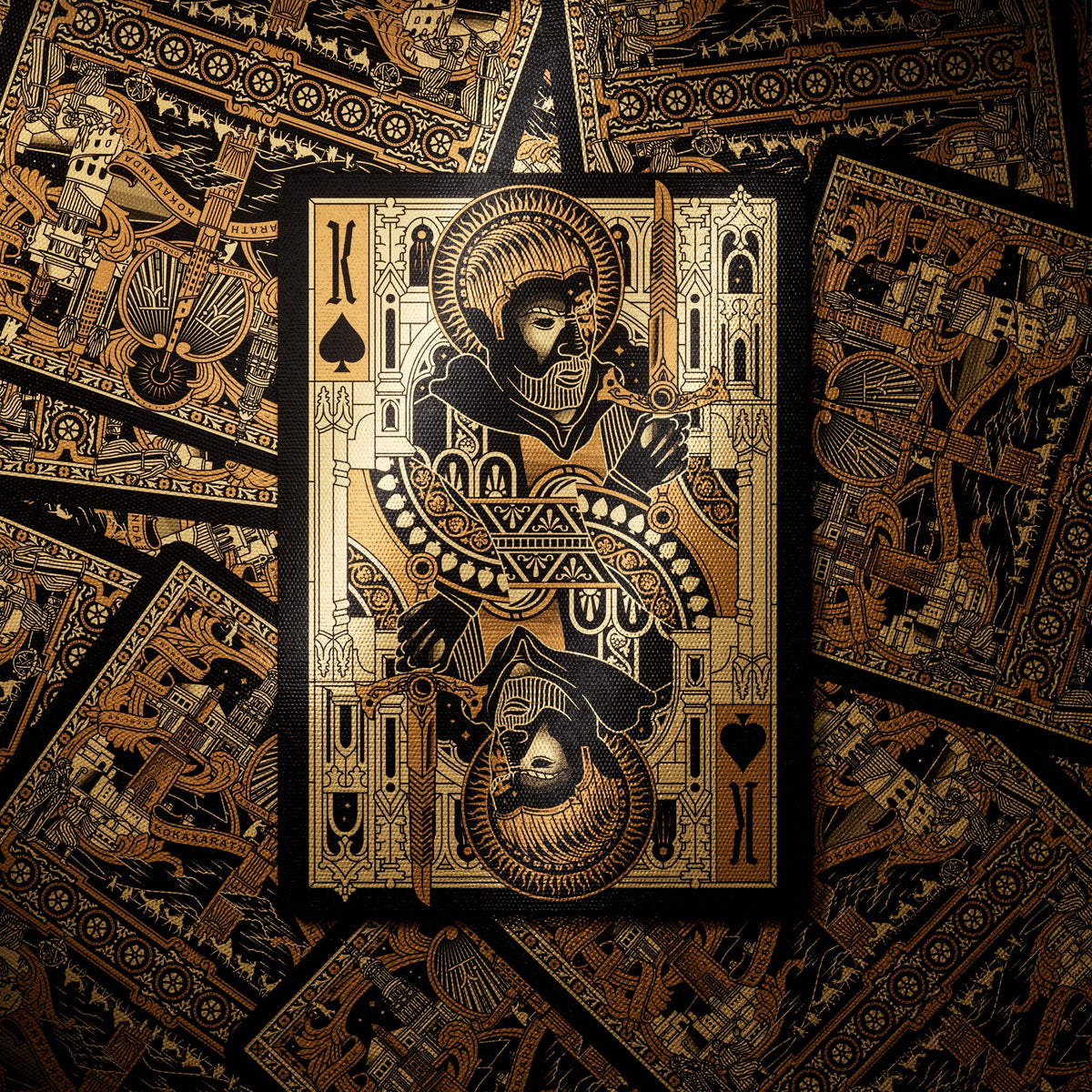 Theory11 Kovadrin King of Spades with custom gold-and-black court artwork displayed over a spread of ornate card backs.