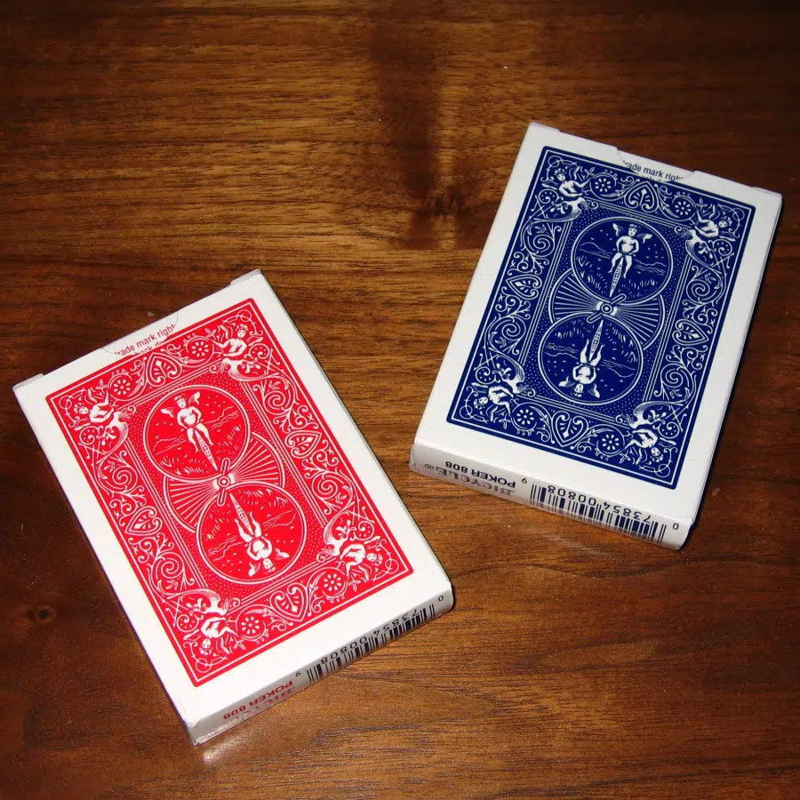 Two decks of Bicycle ultimate marked deck playing cards, one red and one blue, on a wooden surface.
