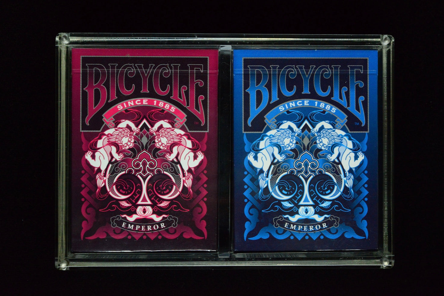 Two Bicycle Emperor playing card decks, one red and one blue, on a black background.