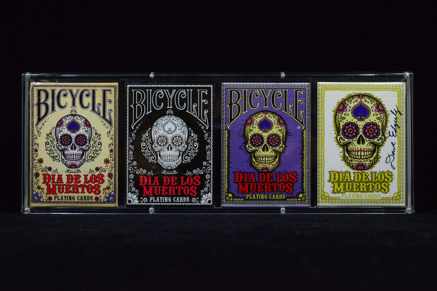 Four Bicycle Dia de los Muertos playing card decks on a black background