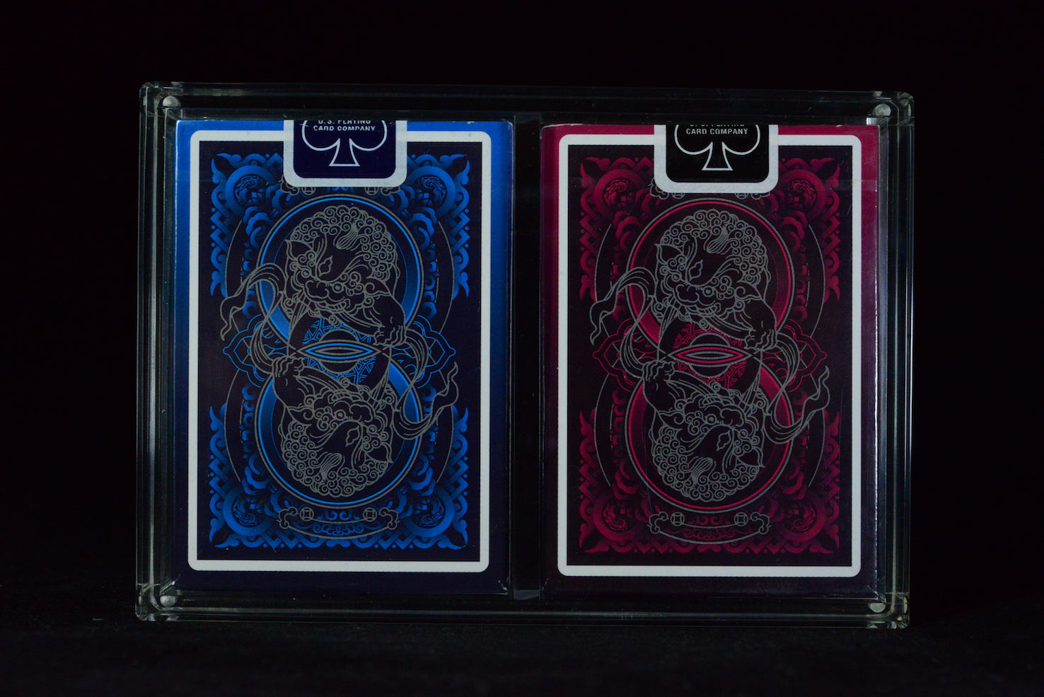 Two playing card decks with blue and red designs on a black background