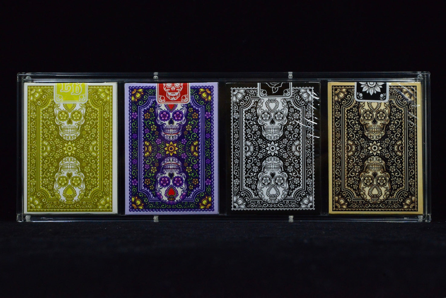 Four playing card decks with skull designs on a black background
