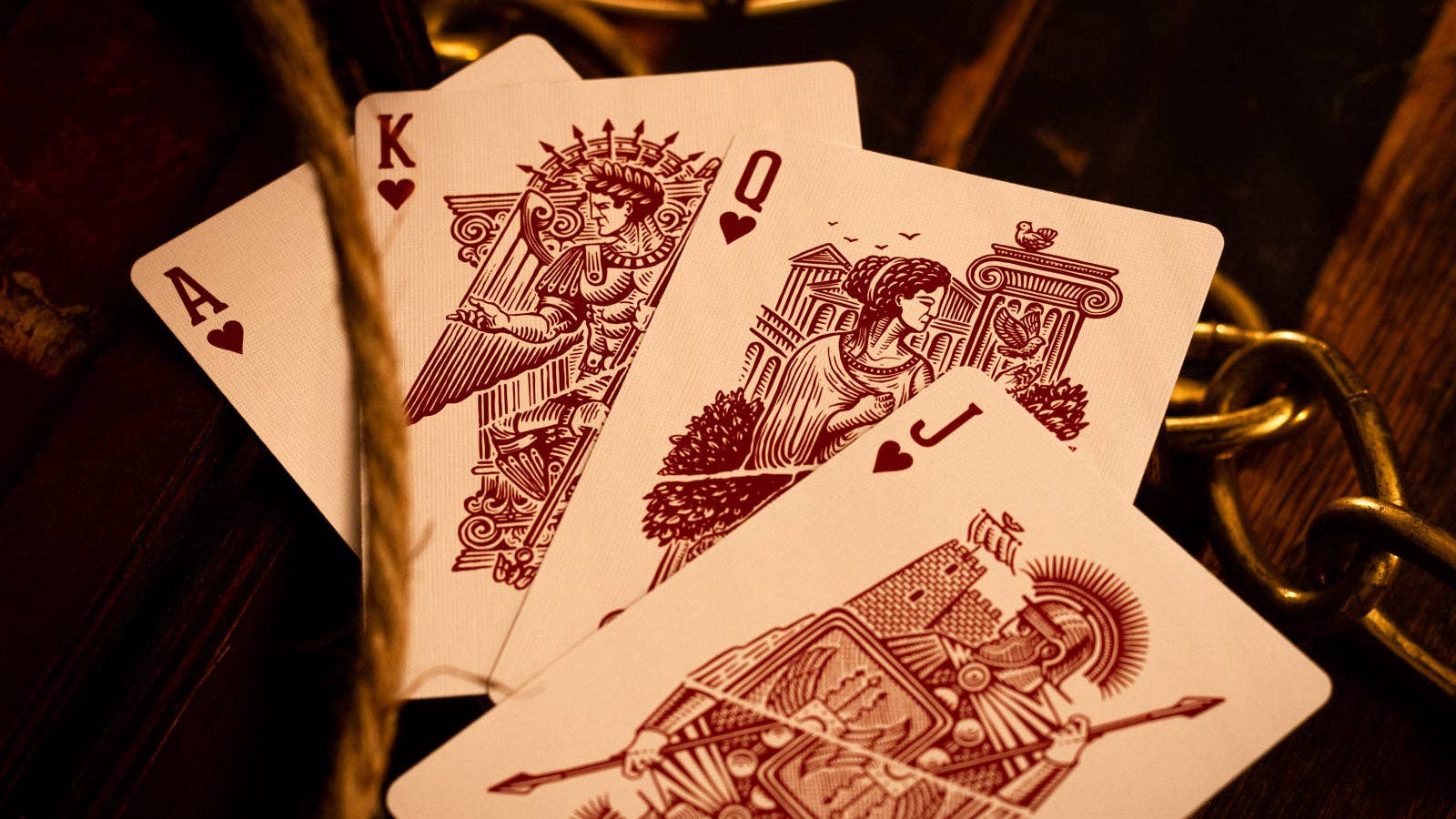 Four Centurio playing cards (King, Queen, King, Ace) on a wooden surface with a warm tone.