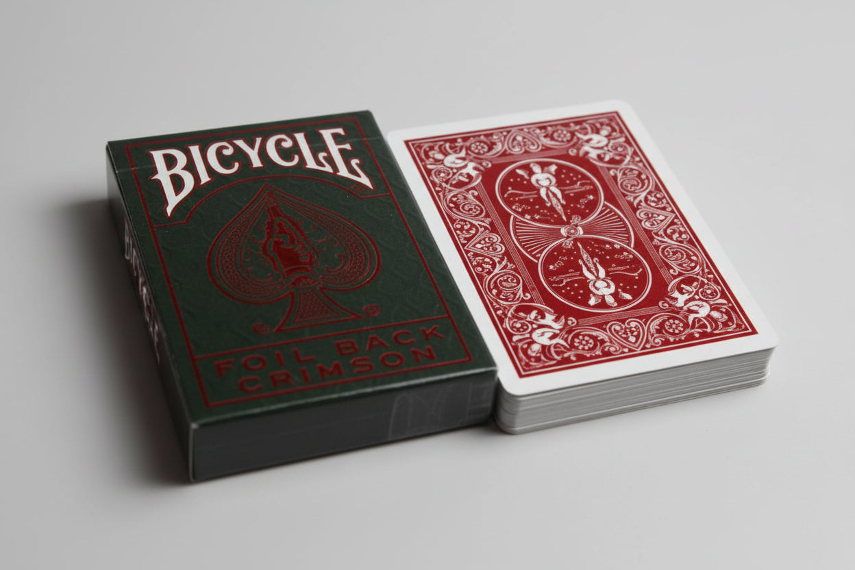 Two playing cards from the Bicycle Metalluxe Foil Crimson deck on a metallic surface.