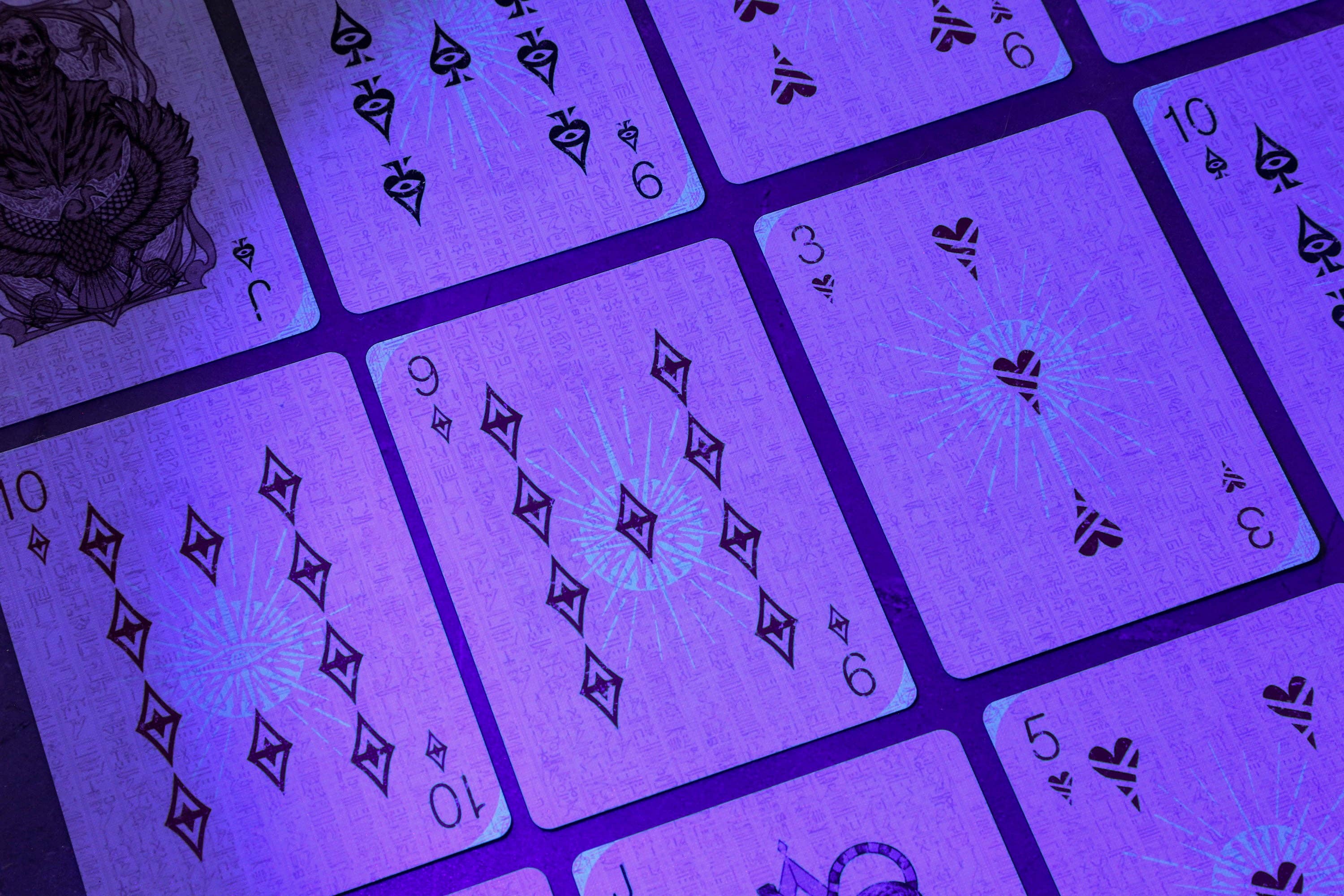 Close-up of playing cards with black symbols under a purple filter