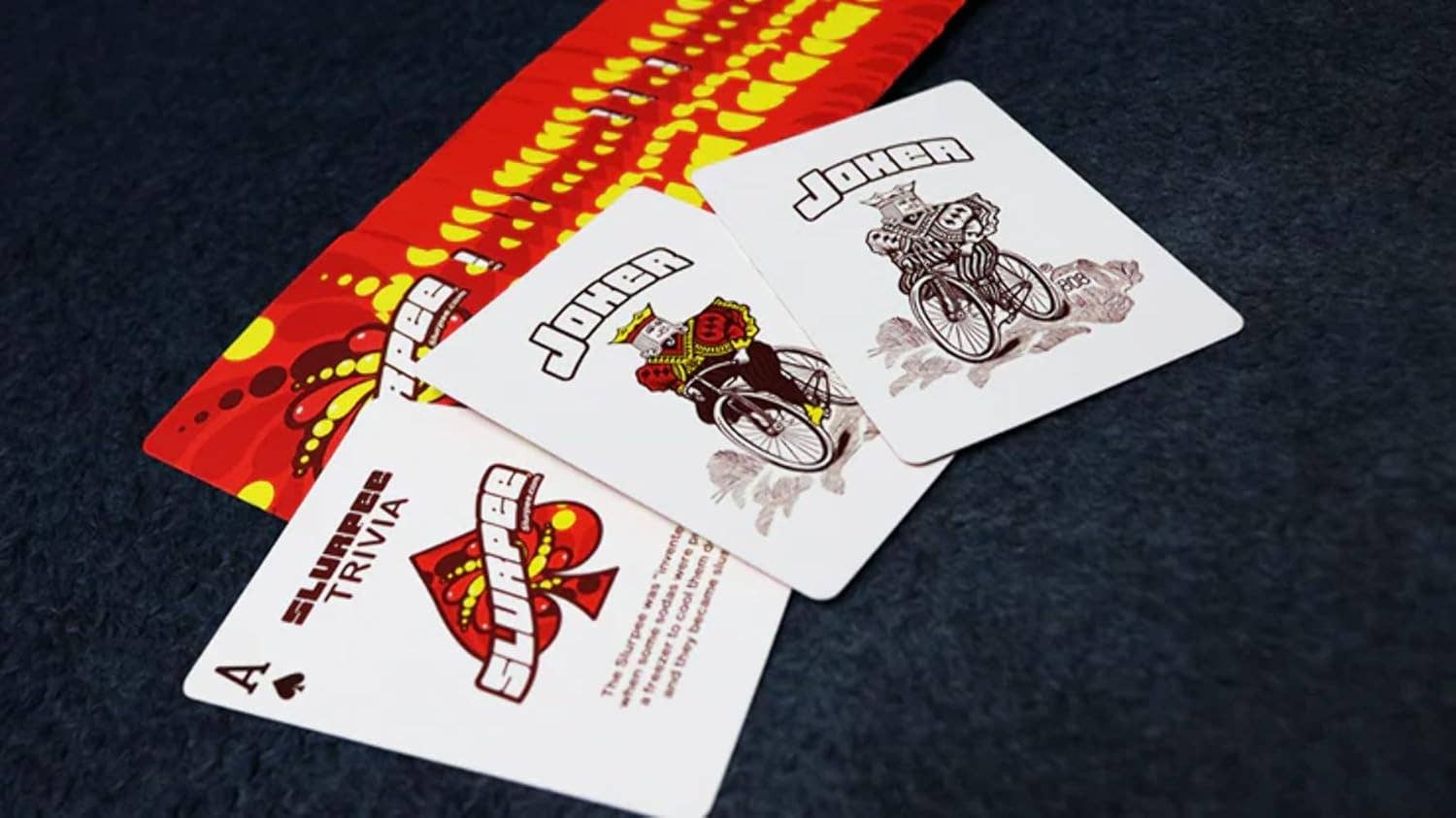 Three playing cards with unique designs on a dark surface