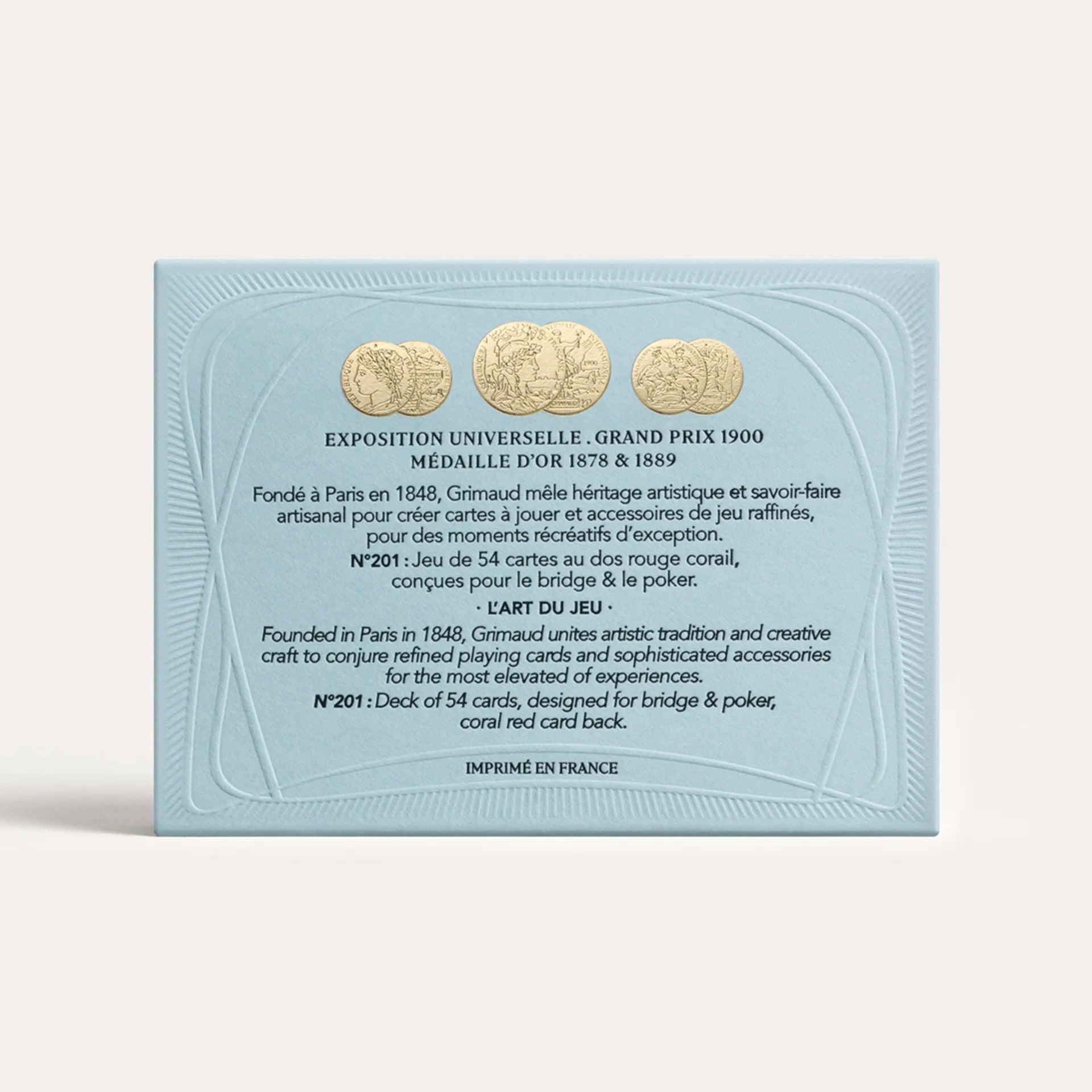 Packaging of Grimaud playing cards with gold coins on a light blue background