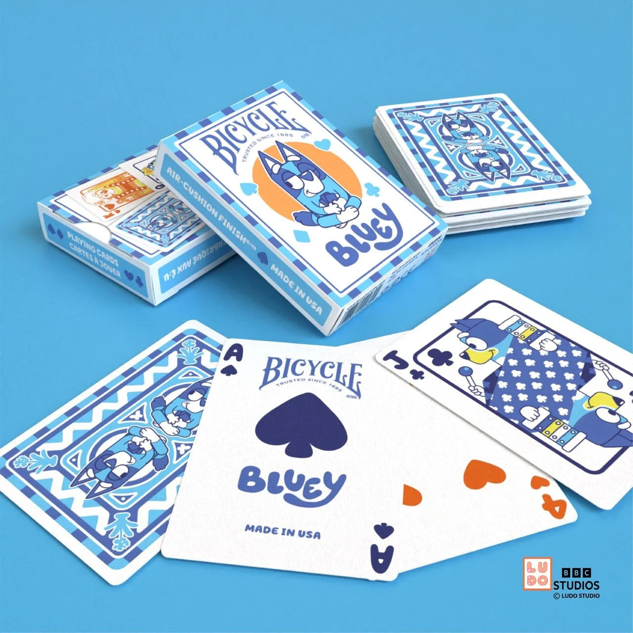 Bicycle Bluey tuck box and cards on blue surface with Ace of Spades Bluey card and custom backs.