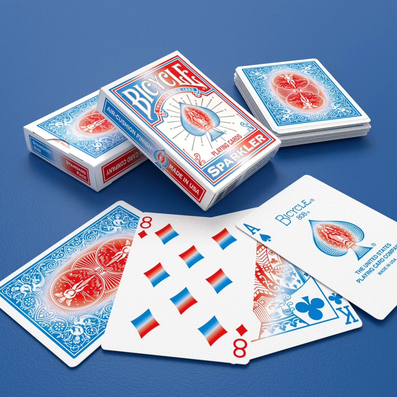 Bicycle Sparkler Playing Cards with white tuck boxes, blue and red rider backs, and colorful pips on blue background