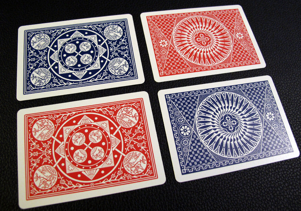 Four playing cards with red and blue designs on a black background