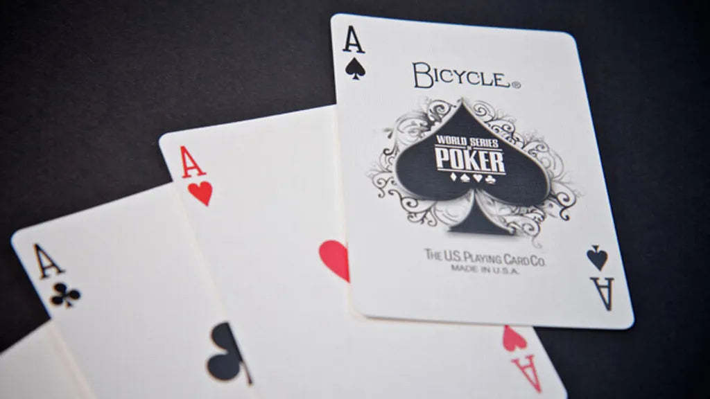 Three Bicycle playing cards, including two aces, on a dark background.