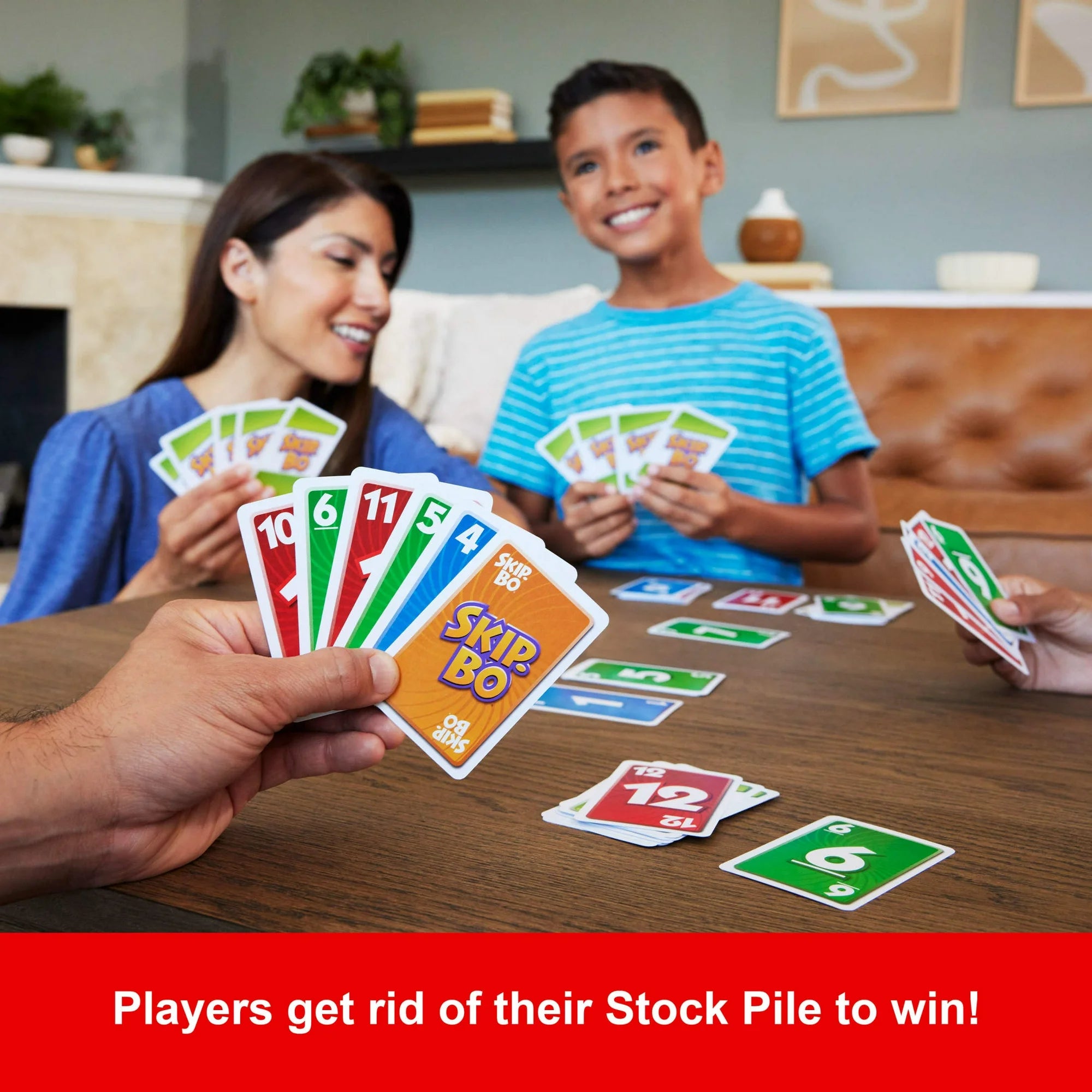 Two children playing Skip-Bo card game with adults around a table.